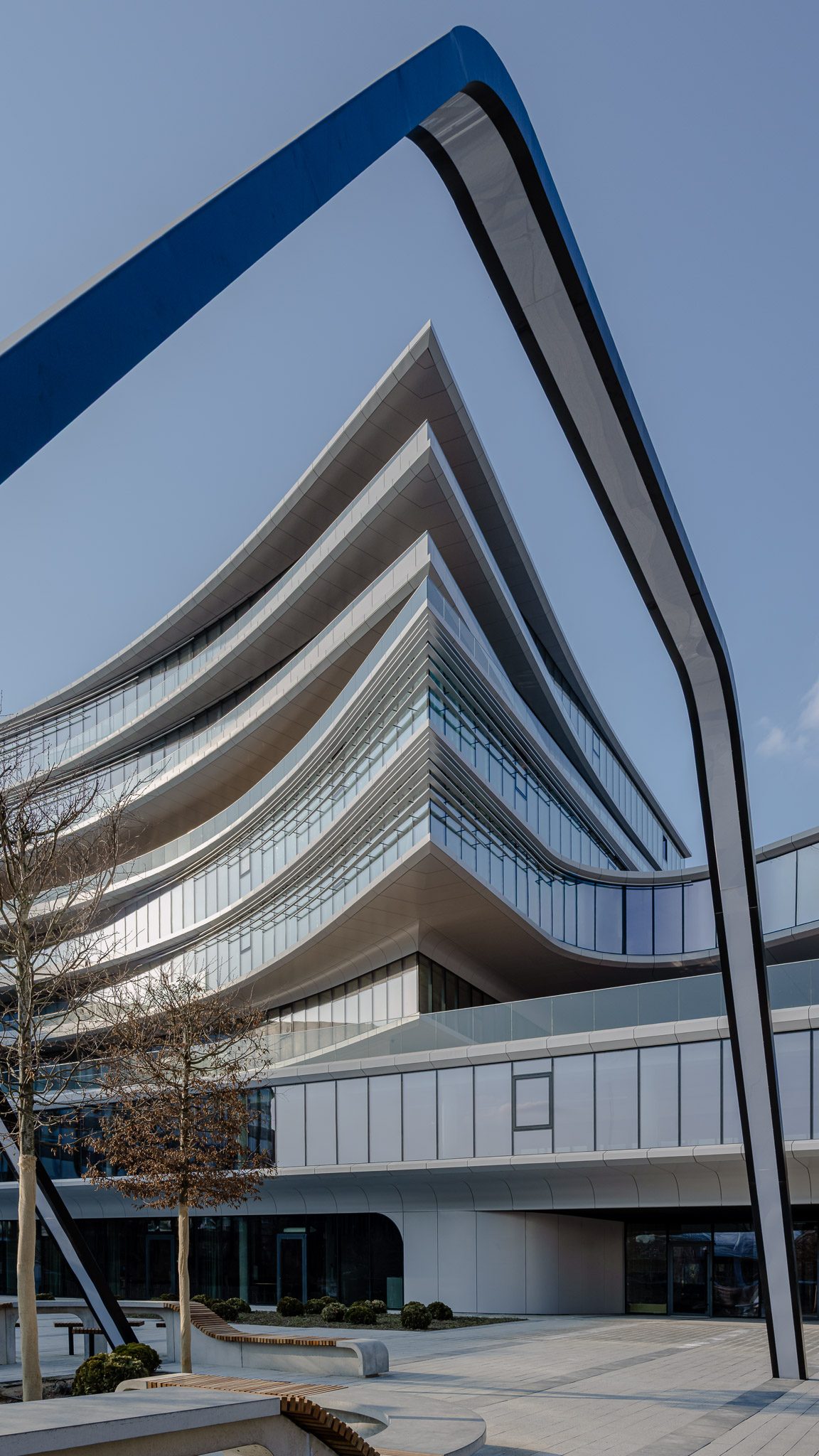 Balcony curves of Business Stadium Central framed by a blue steel arch