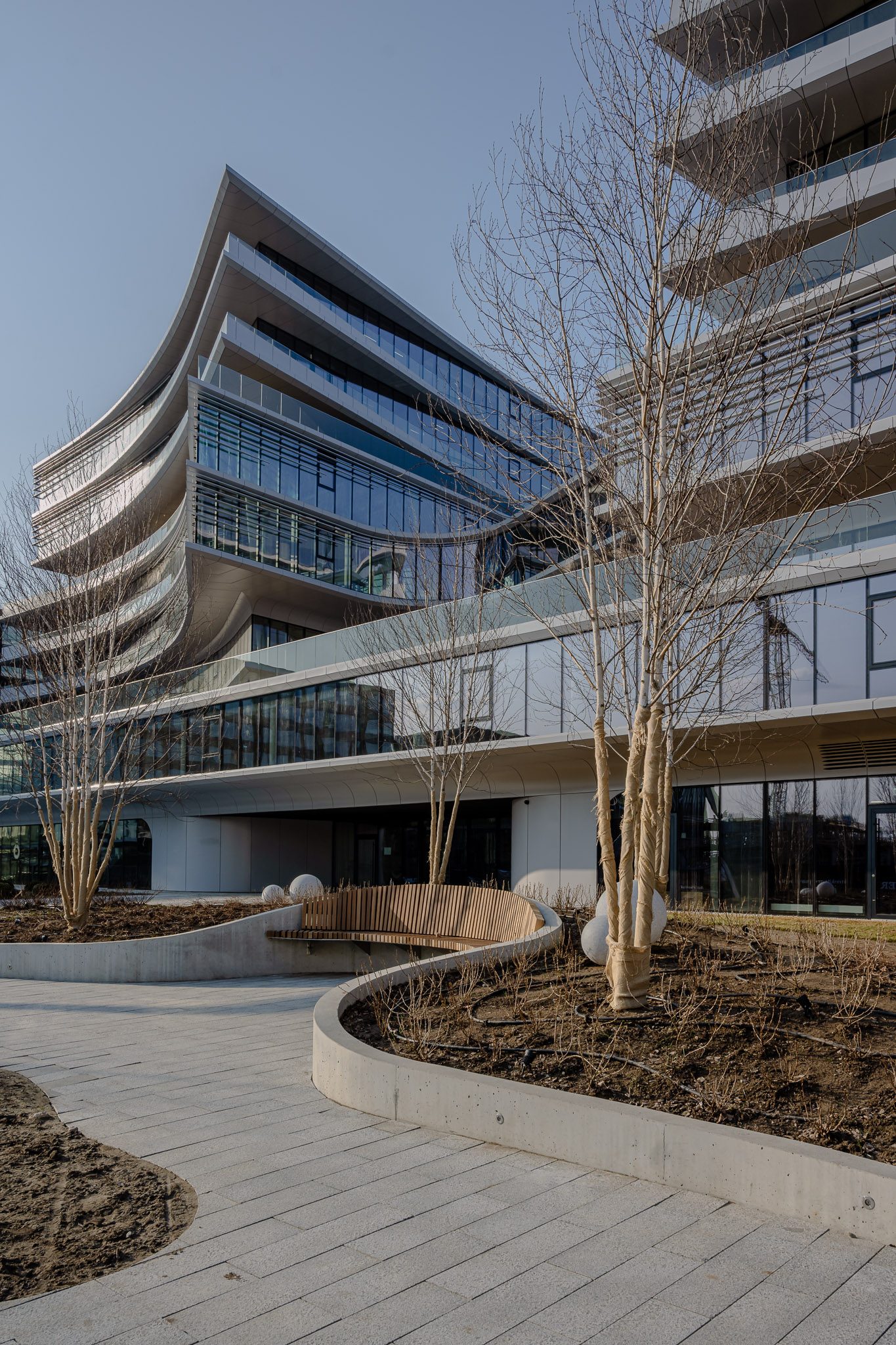 Landscaped courtyard path curving beneath the floor plates of Business Stadium Central