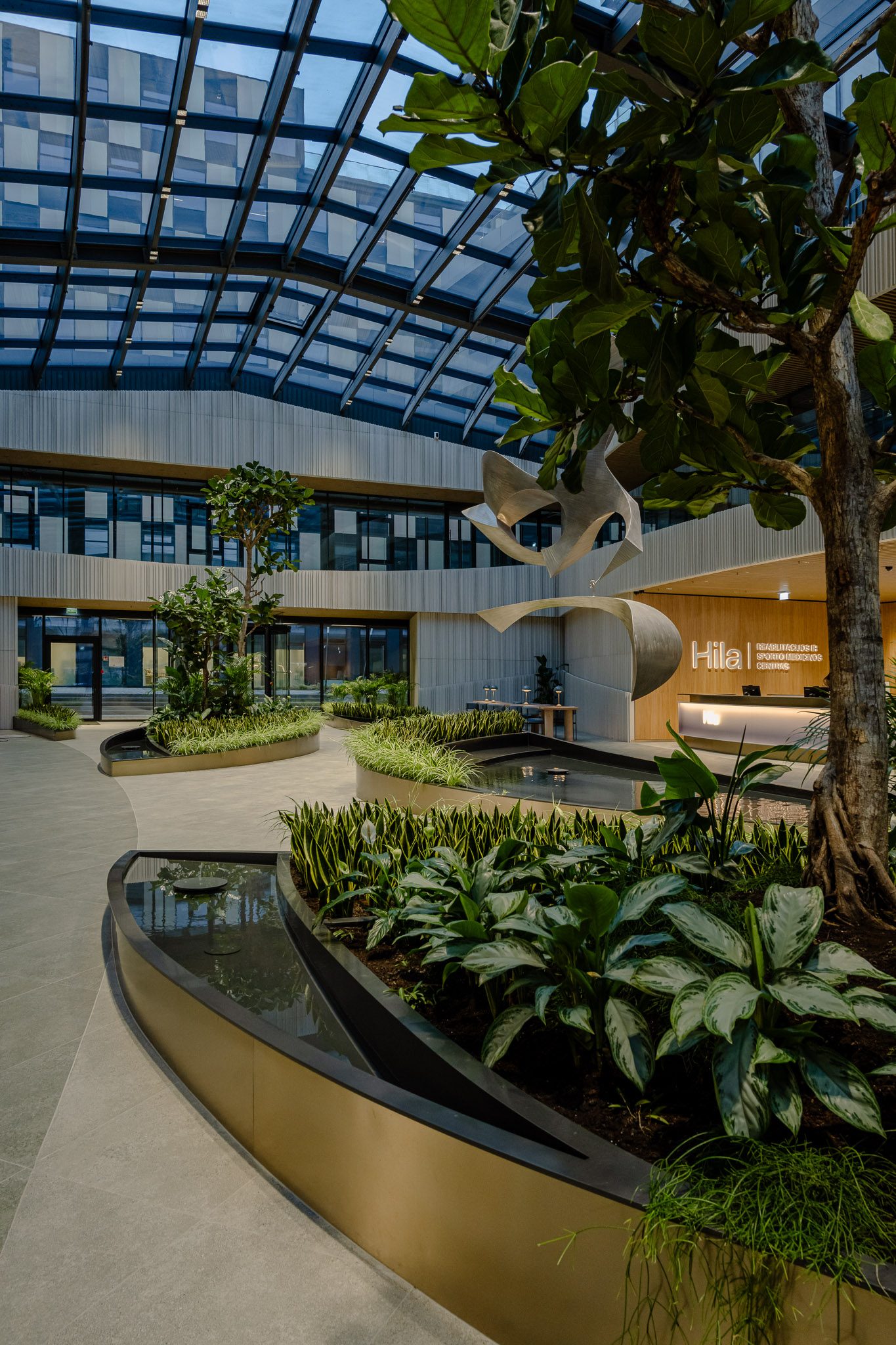 Planting and water channel in the glazed atrium of Business Stadium Central