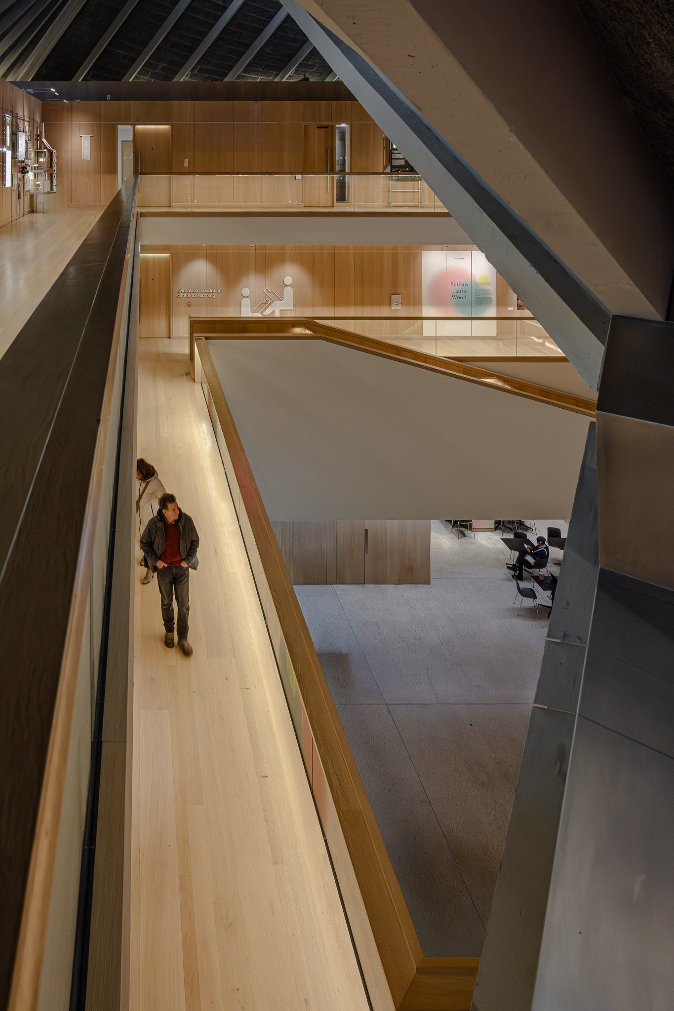 Visitor on an oak walkway beside the atrium void, Design Museum
