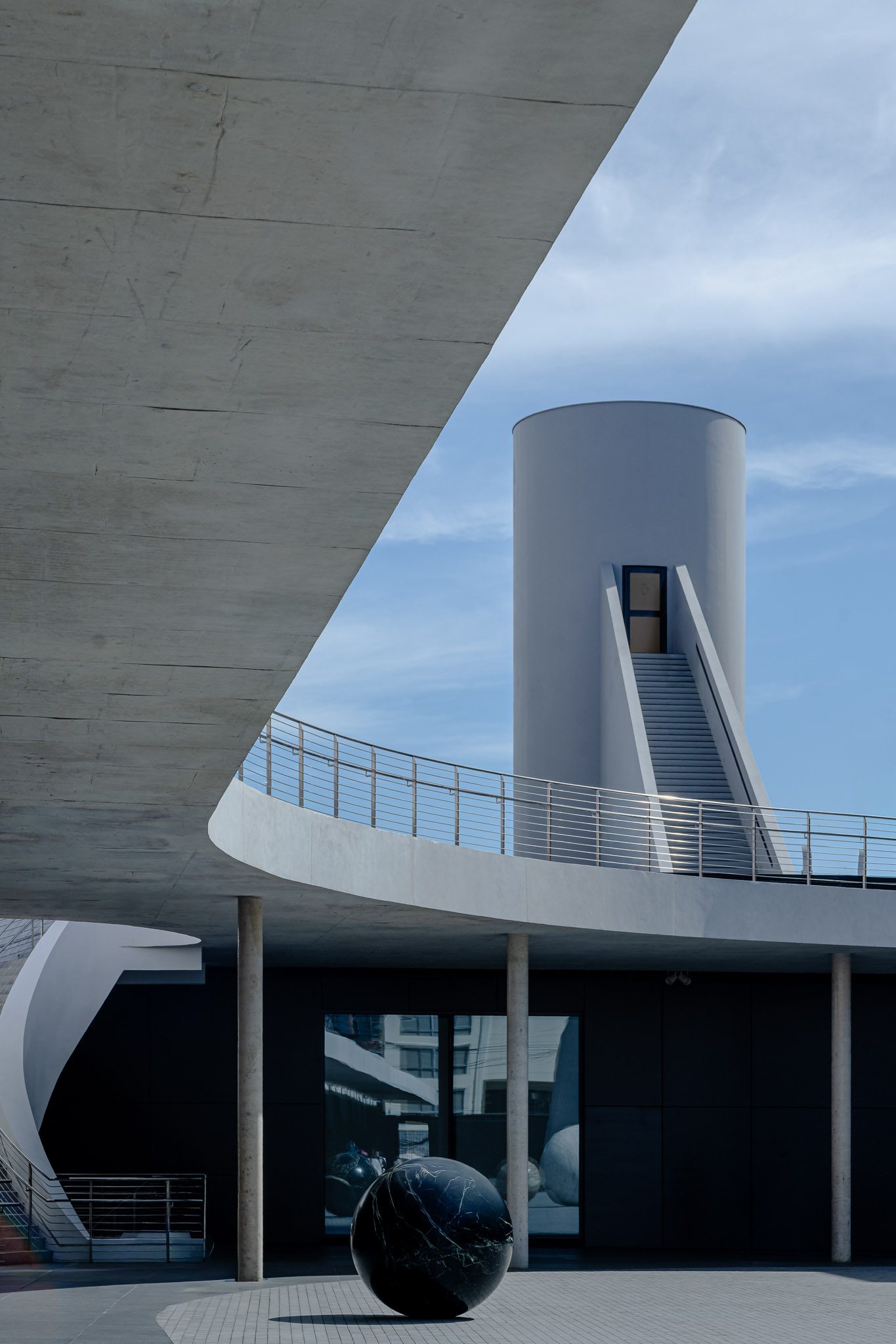 Cylindrical tower and stair seen beneath a concrete canopy, Dib Bangkok