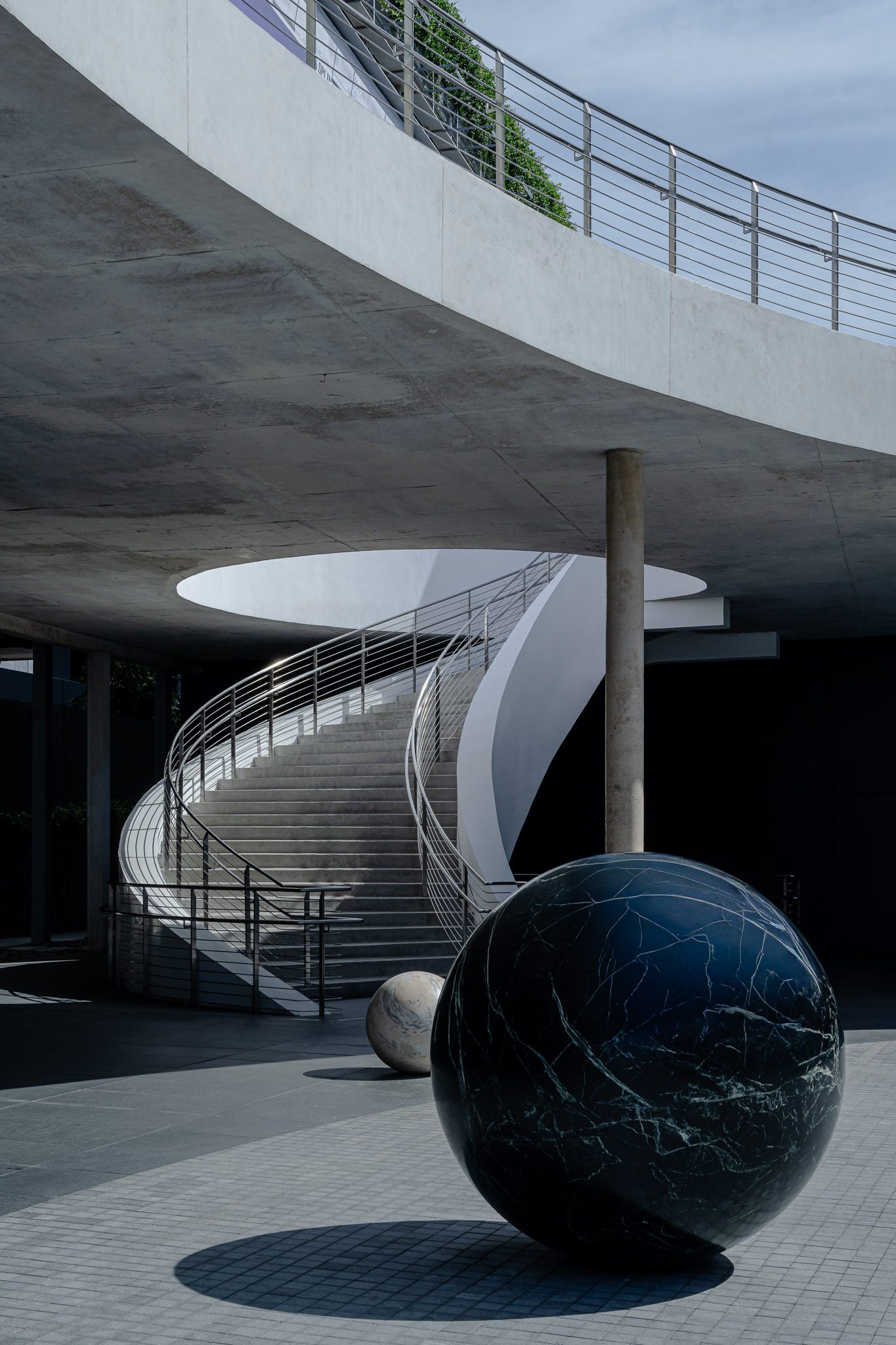 Spiral stair and black marble sphere under a circular skylight, Dib Bangkok