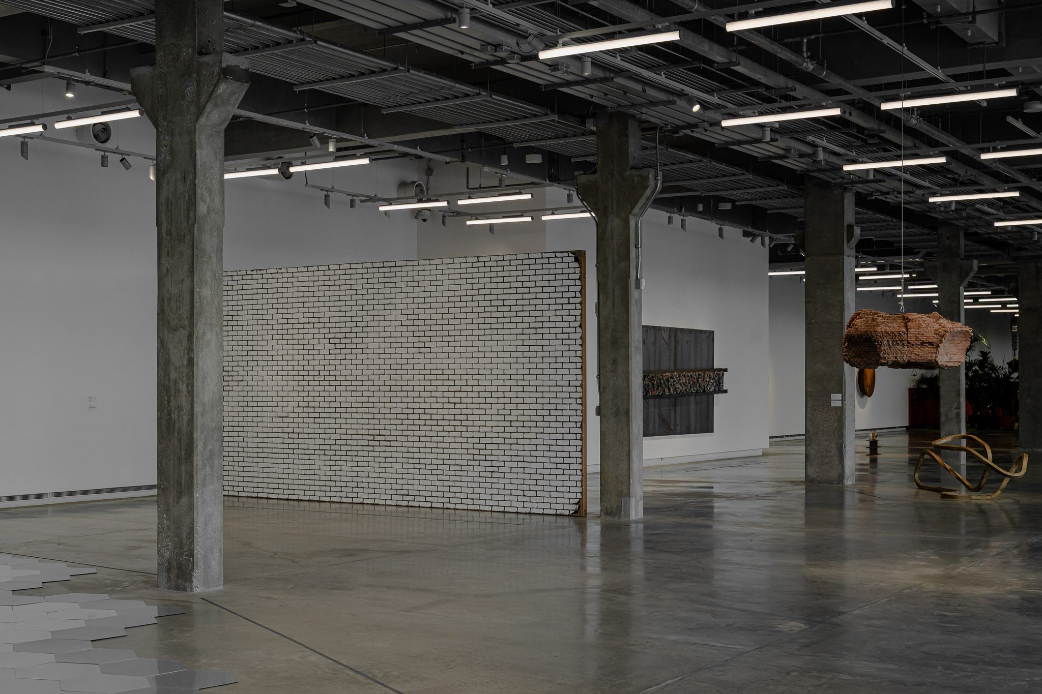 Warehouse gallery with concrete columns and a brick installation, Dib Bangkok