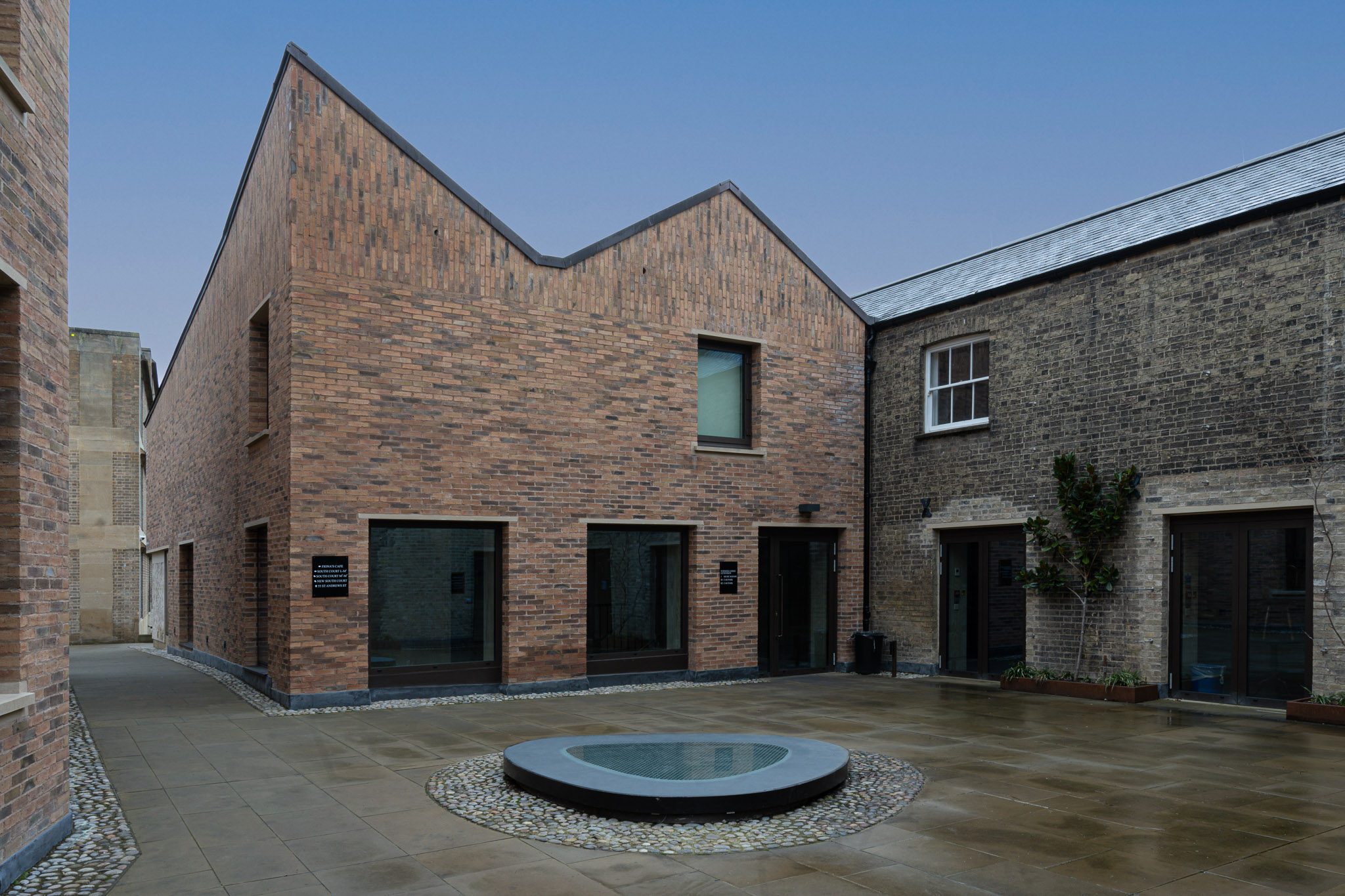 Zigzag brick gables around a courtyard with a round pool, Emmanuel College