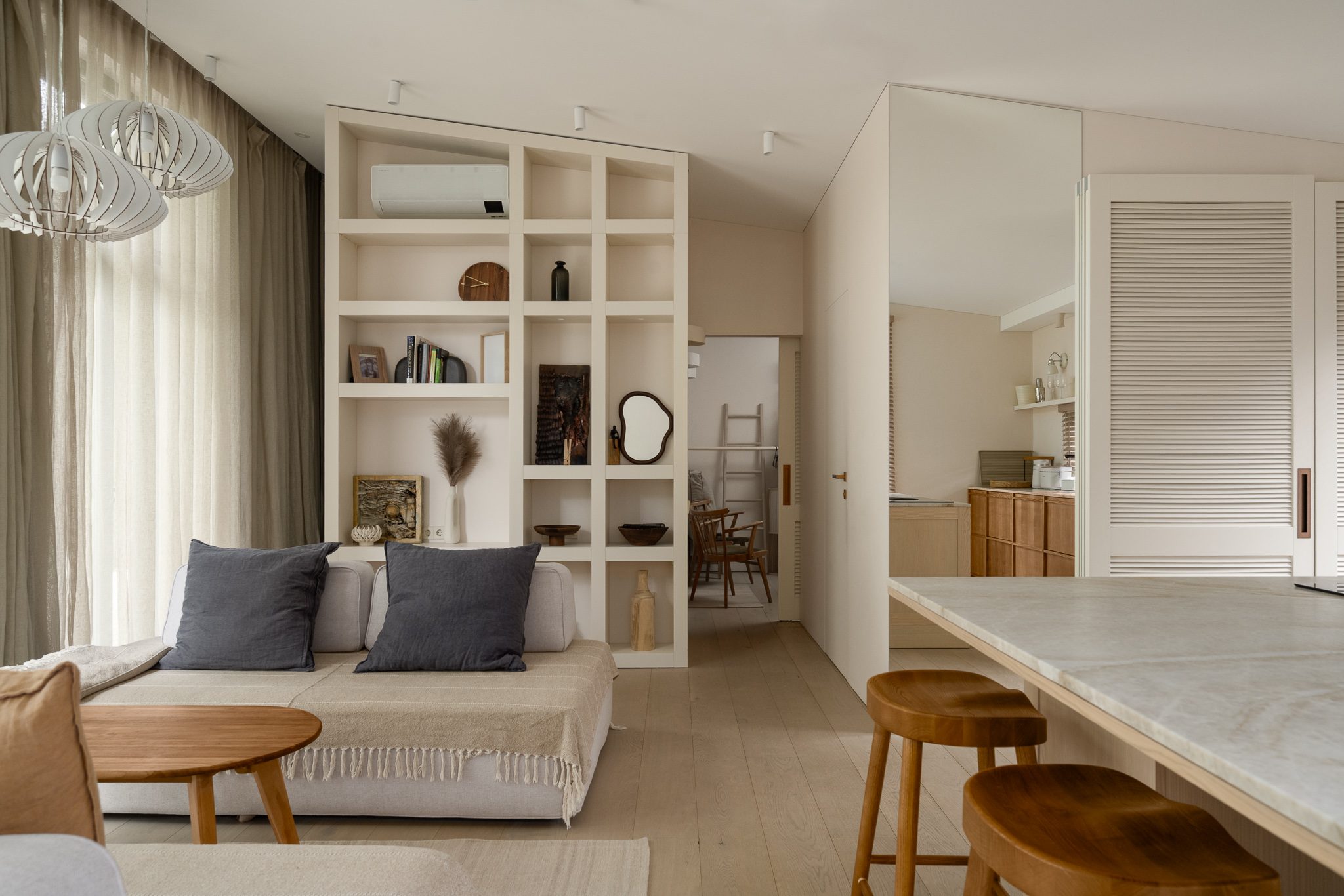 Living area with daybed, open shelving and the kitchen island beyond
