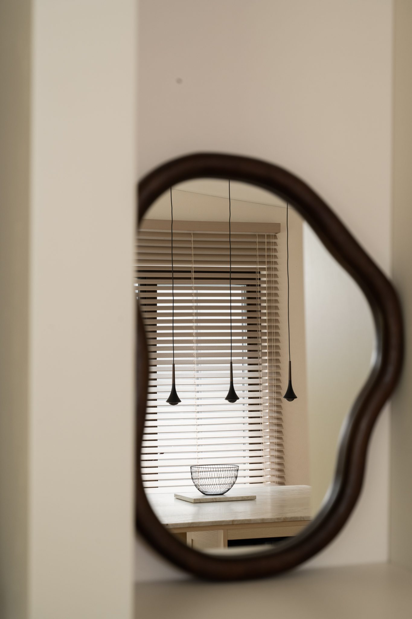 Organic mirror reflecting pendant lights and blinds