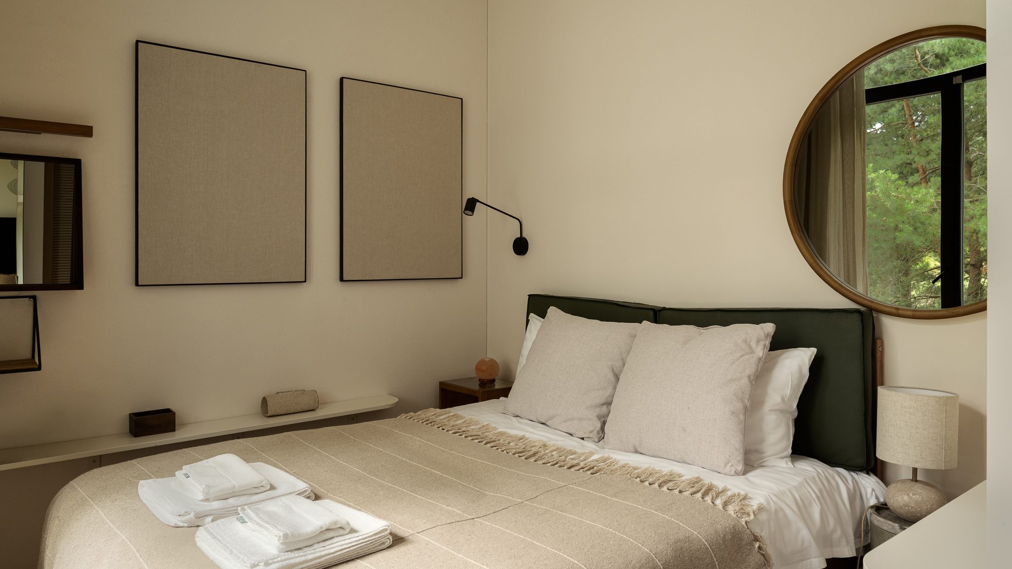 Bedroom with a green headboard and round mirror, Forest Edge House