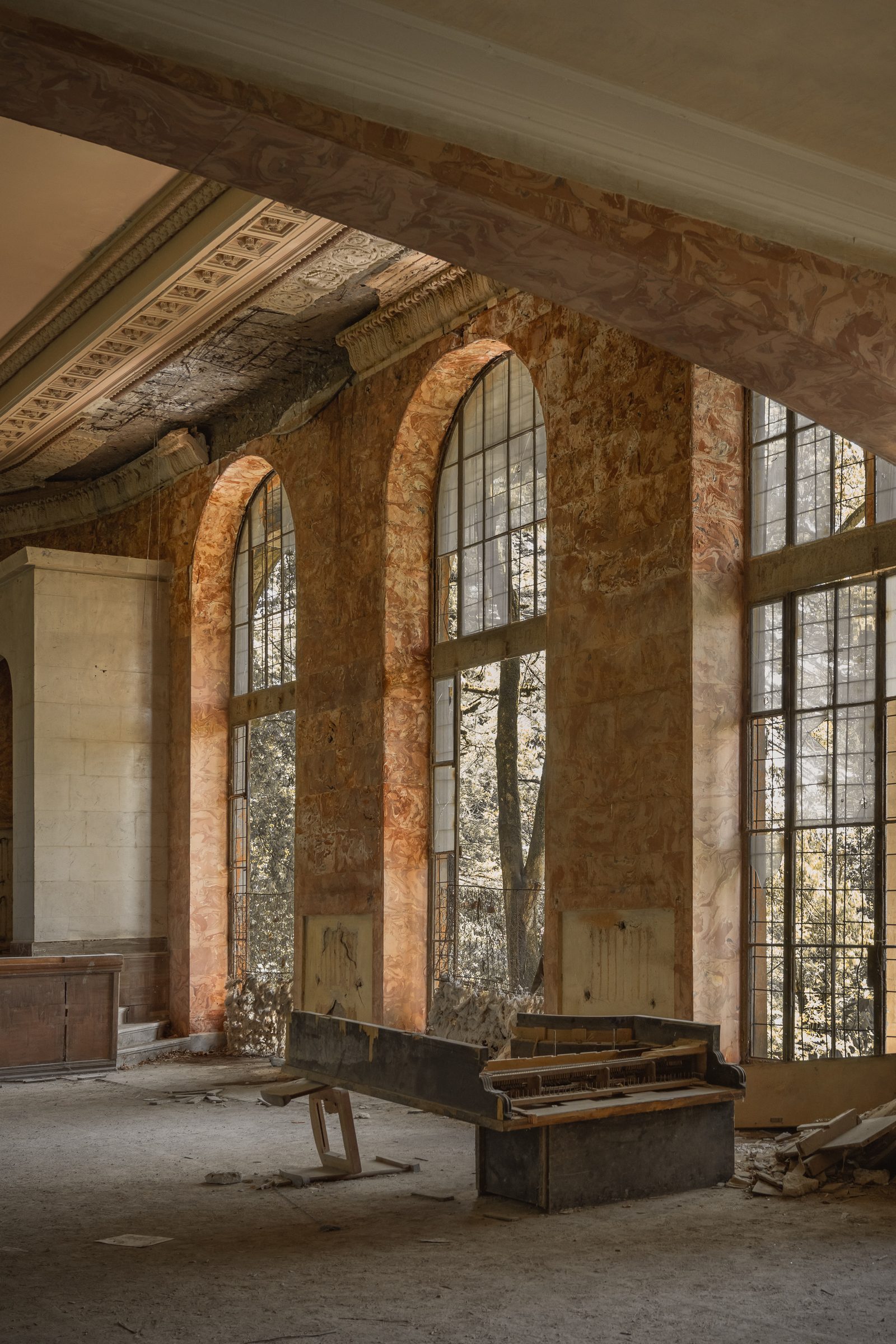 Hall with tall arched windows and an abandoned piano, Sanatorium Metallurgist