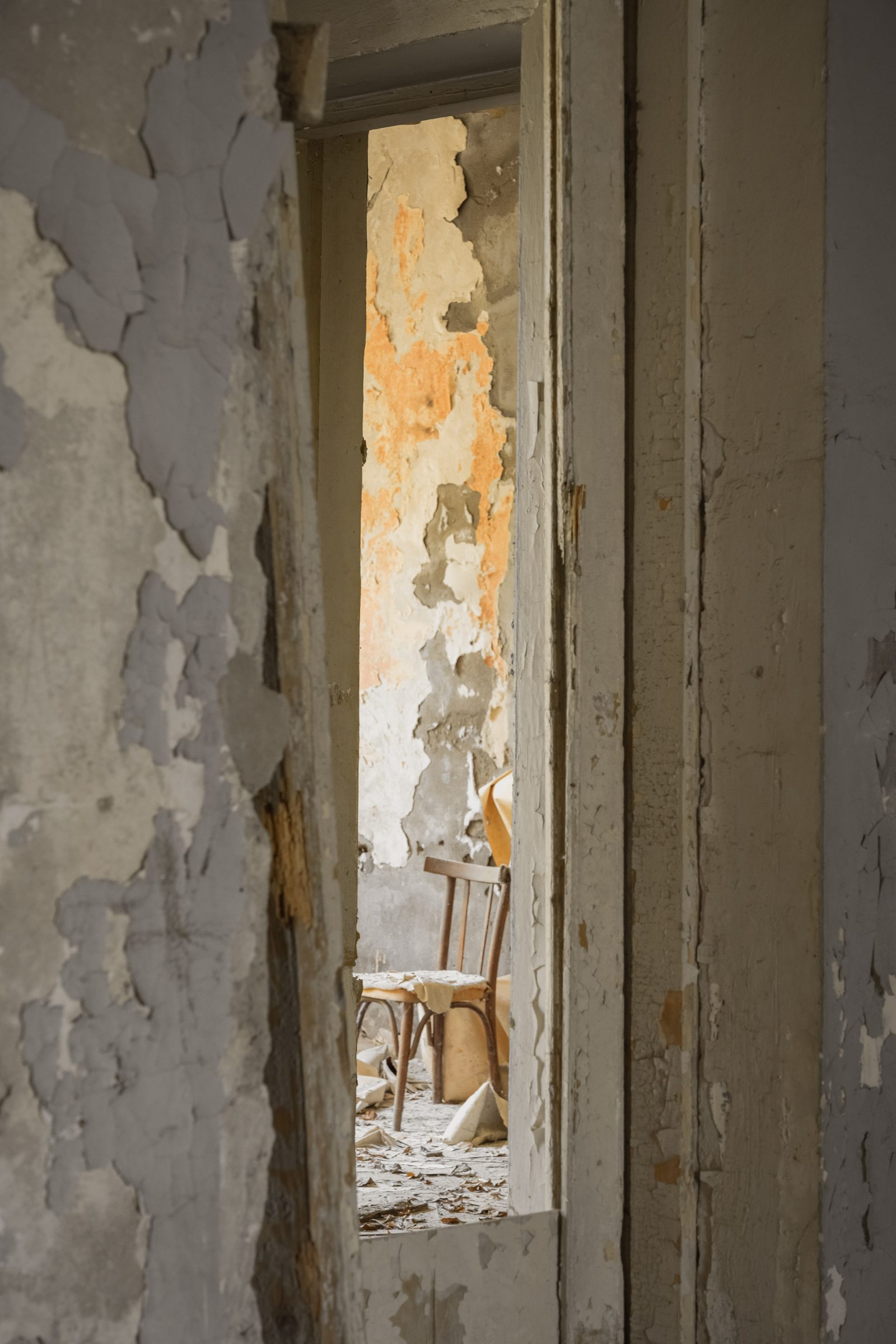 A chair glimpsed through a gap in a peeling doorframe, Sanatorium Metallurgist