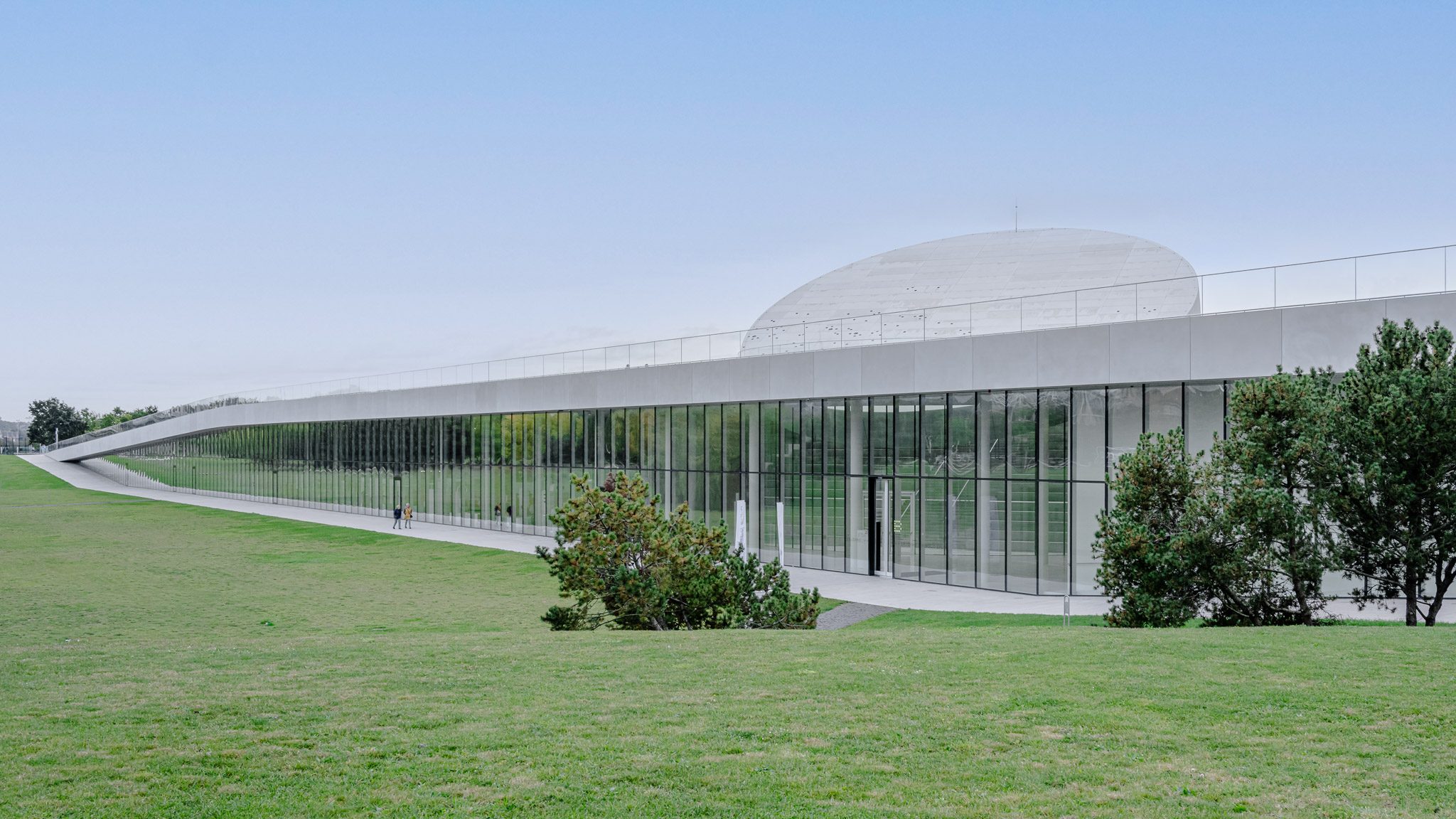 Long glazed museum with a walkable green roof and tilted disc, Mokslo Sala, Kaunas