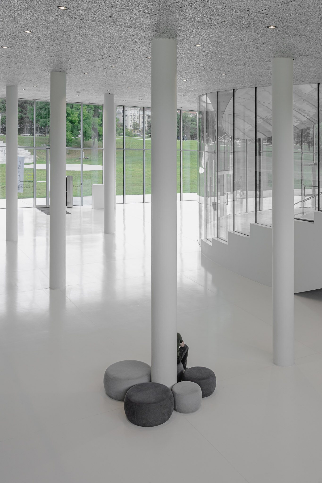 Grey stools around a white column in the foyer, Mokslo Sala