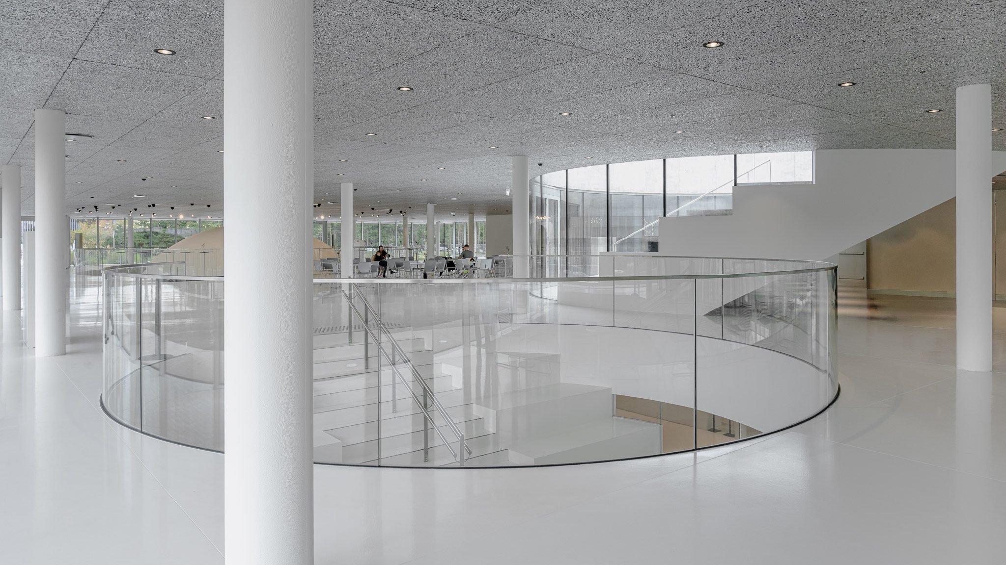 Circular void with a glass balustrade in the white interior, Mokslo Sala
