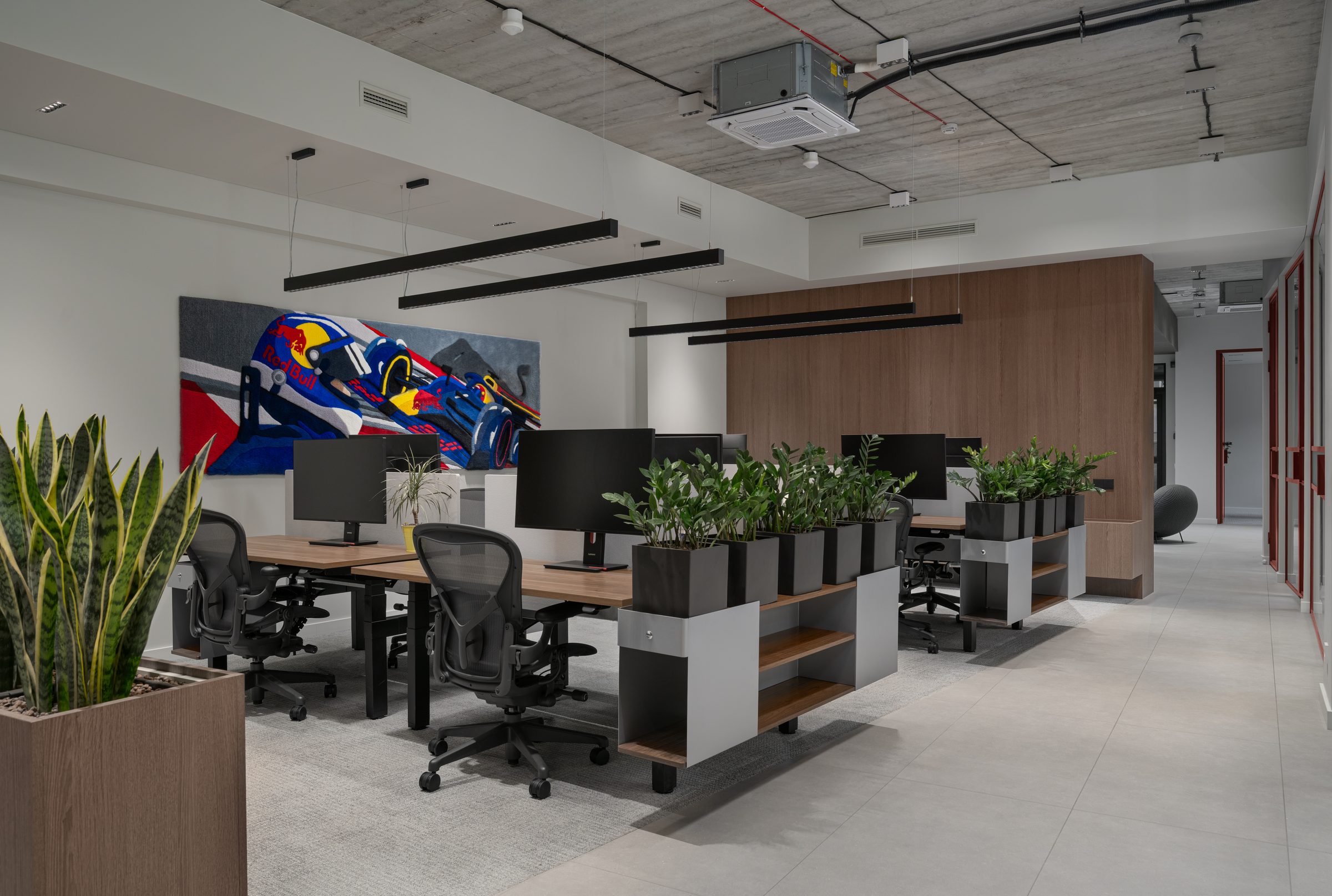 Open workspace with racing-car artwork and planted desks, Red Bull office