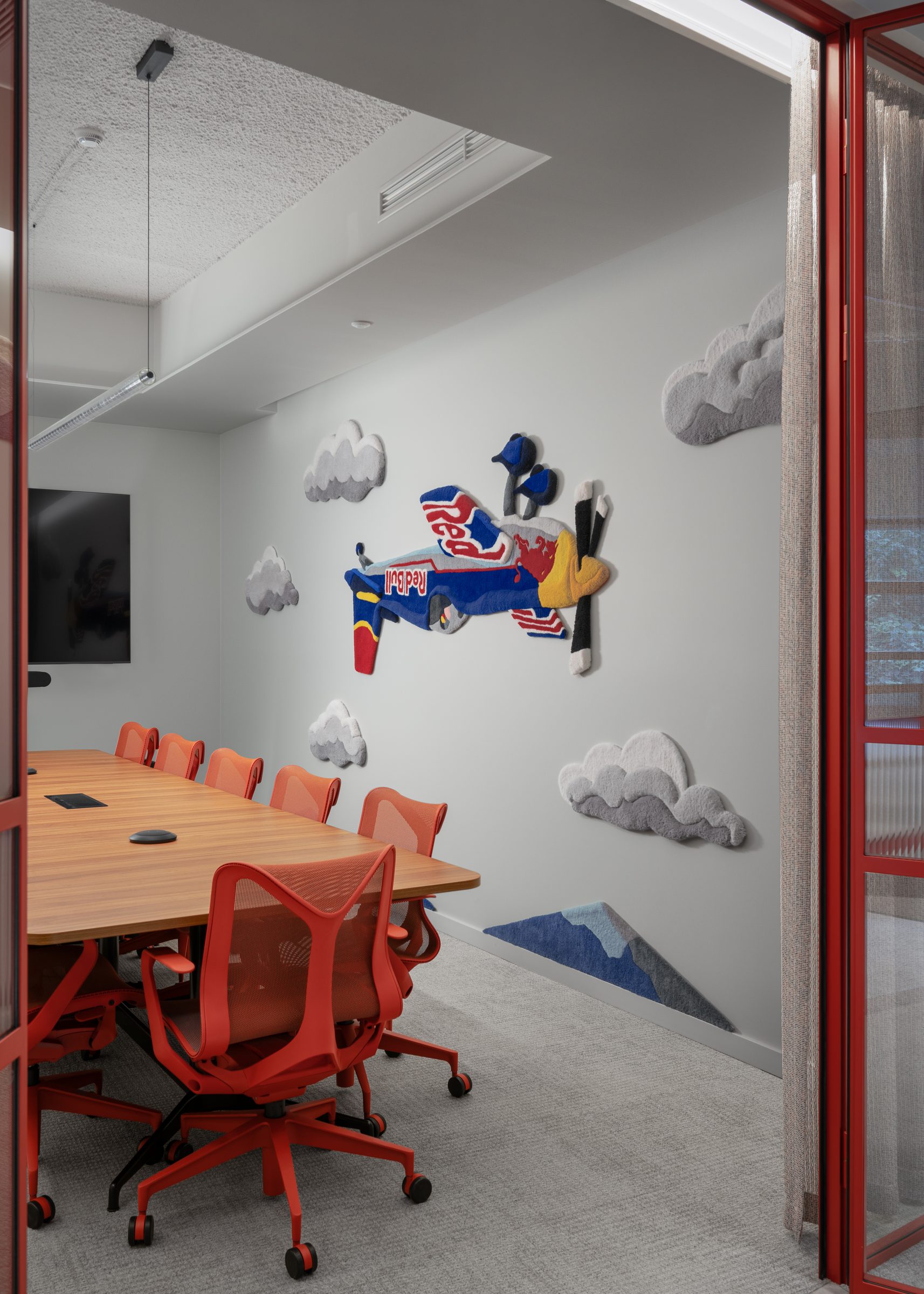 Boardroom with red chairs and an aircraft wall sculpture, Red Bull office