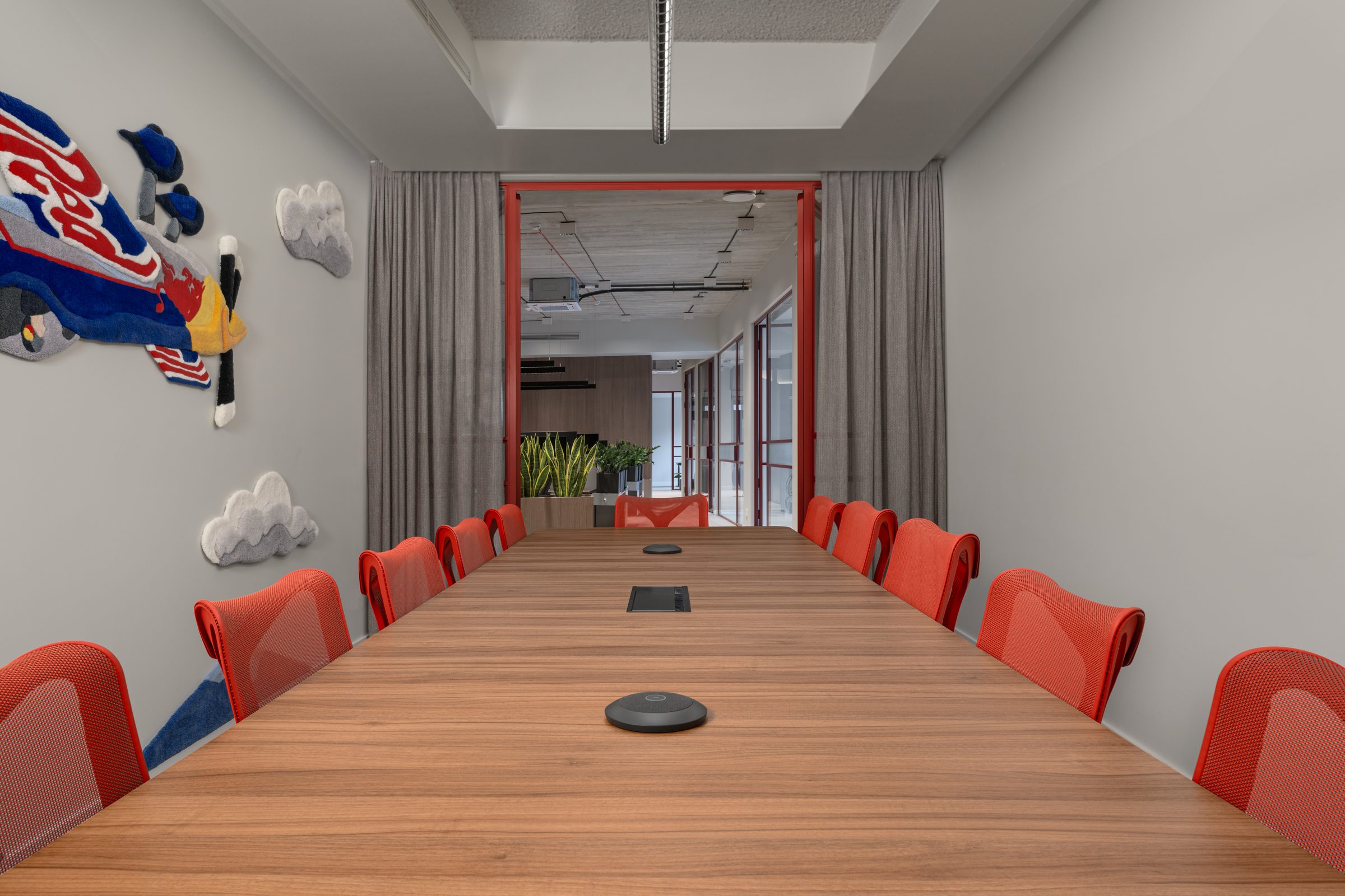 Long boardroom table with red chairs and red-framed glazing, Red Bull office