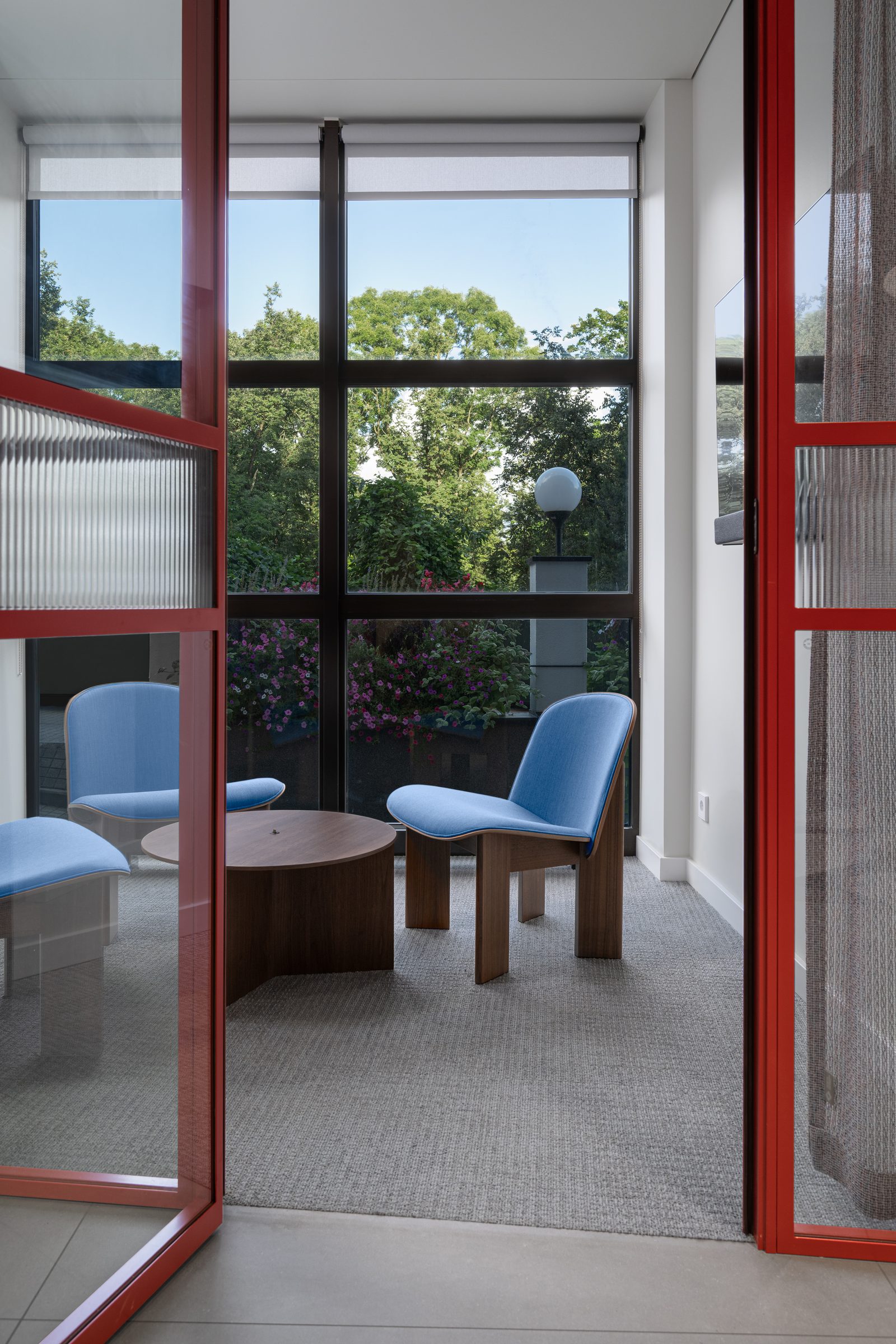 Meeting room with blue lounge chairs behind red-framed glass doors, Red Bull office