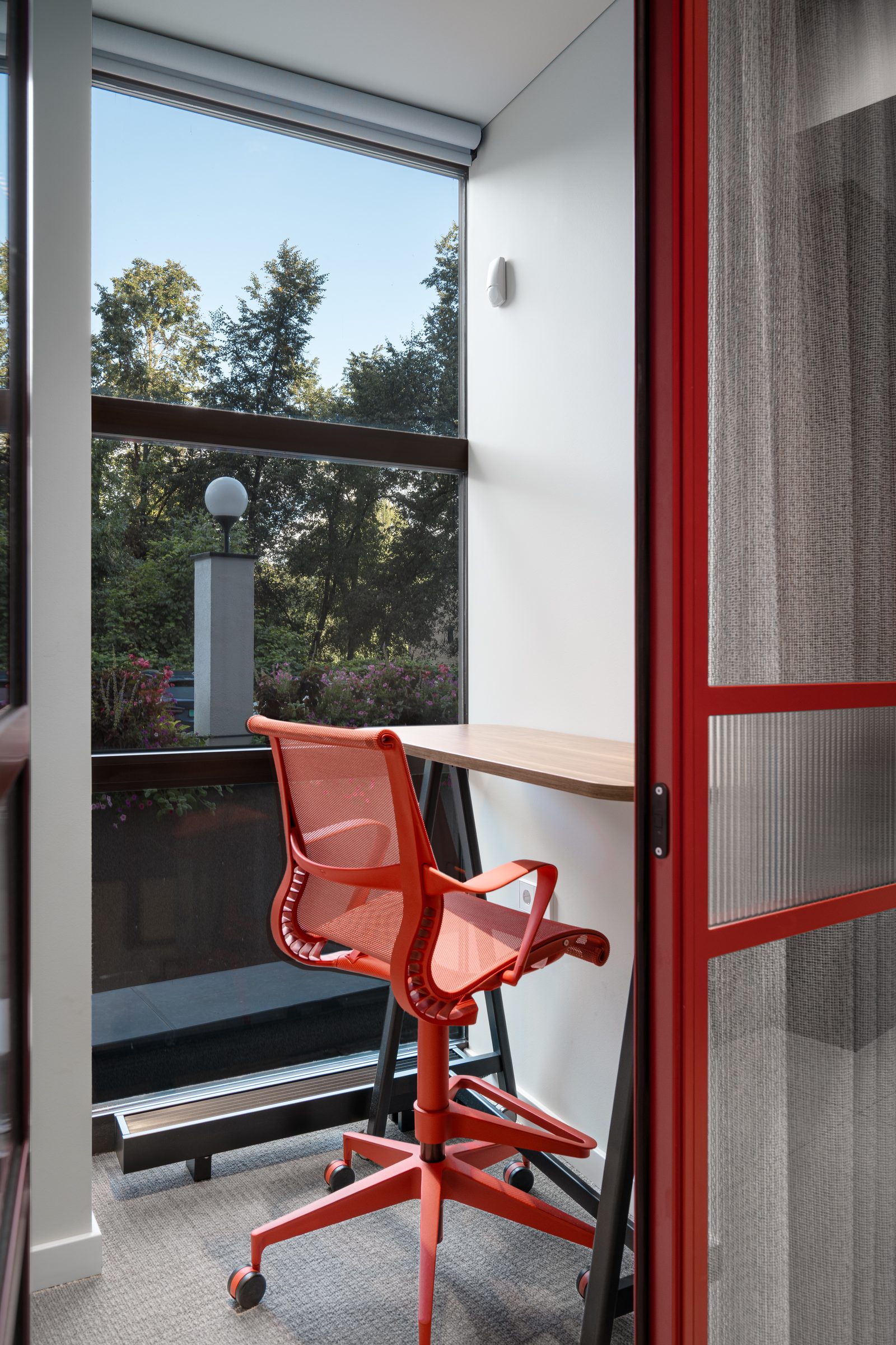 Focus room with a red chair at a window onto the trees, Red Bull office
