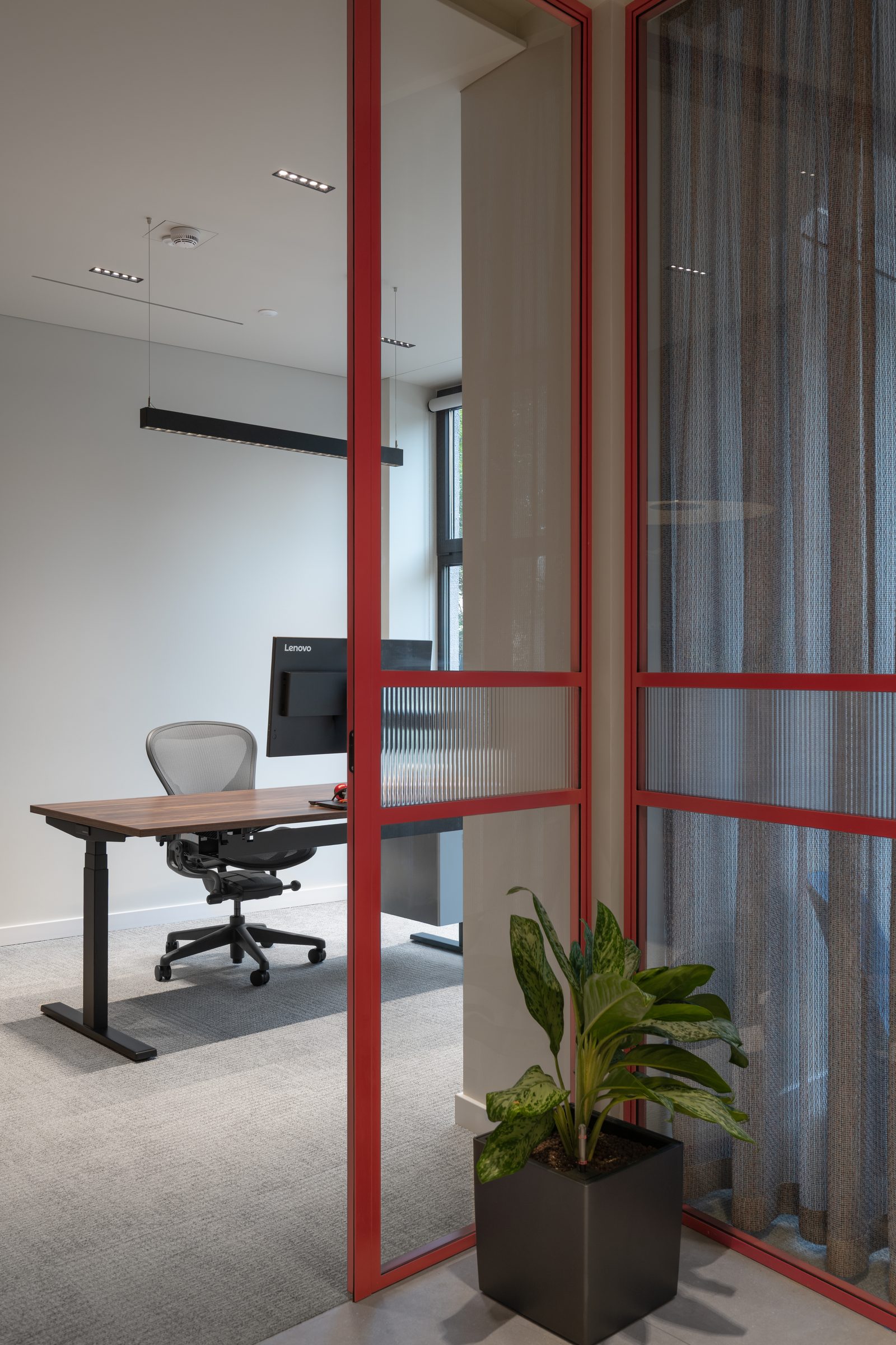 Corner office seen through red-framed glass, Red Bull office