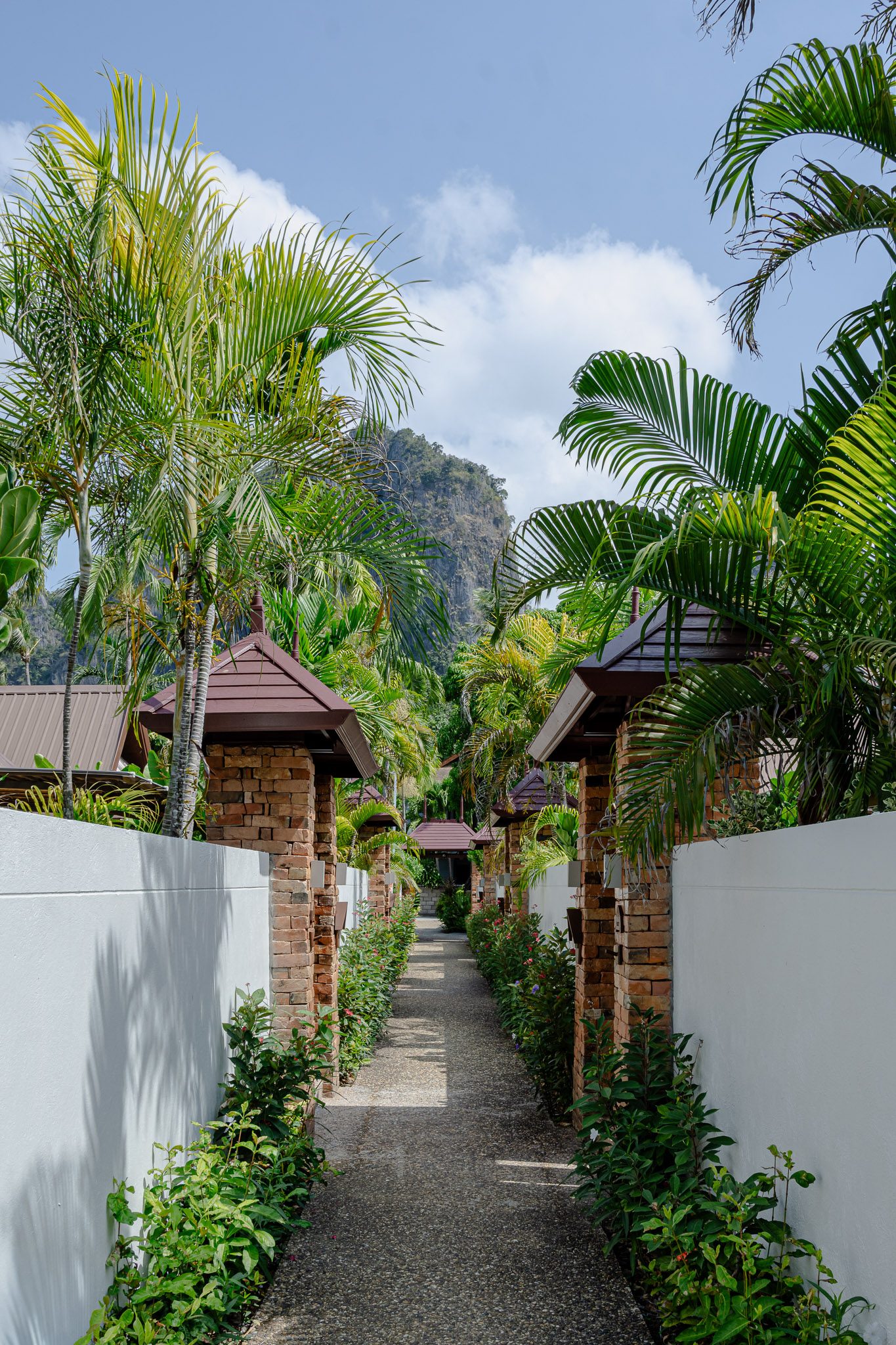 Garden path between white walls beneath limestone cliffs, Thai Cottage, Thailand