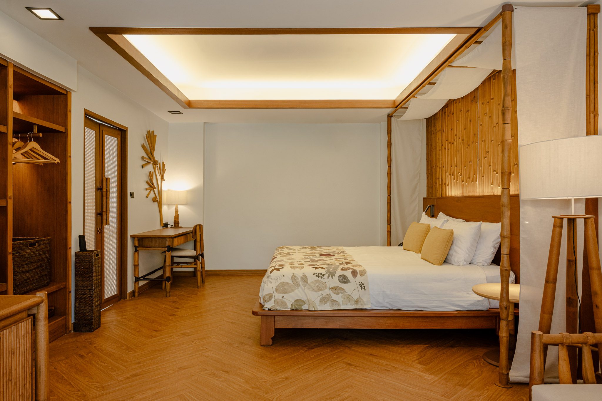 Bedroom with a bamboo four-poster bed and herringbone floor, Thai Cottage